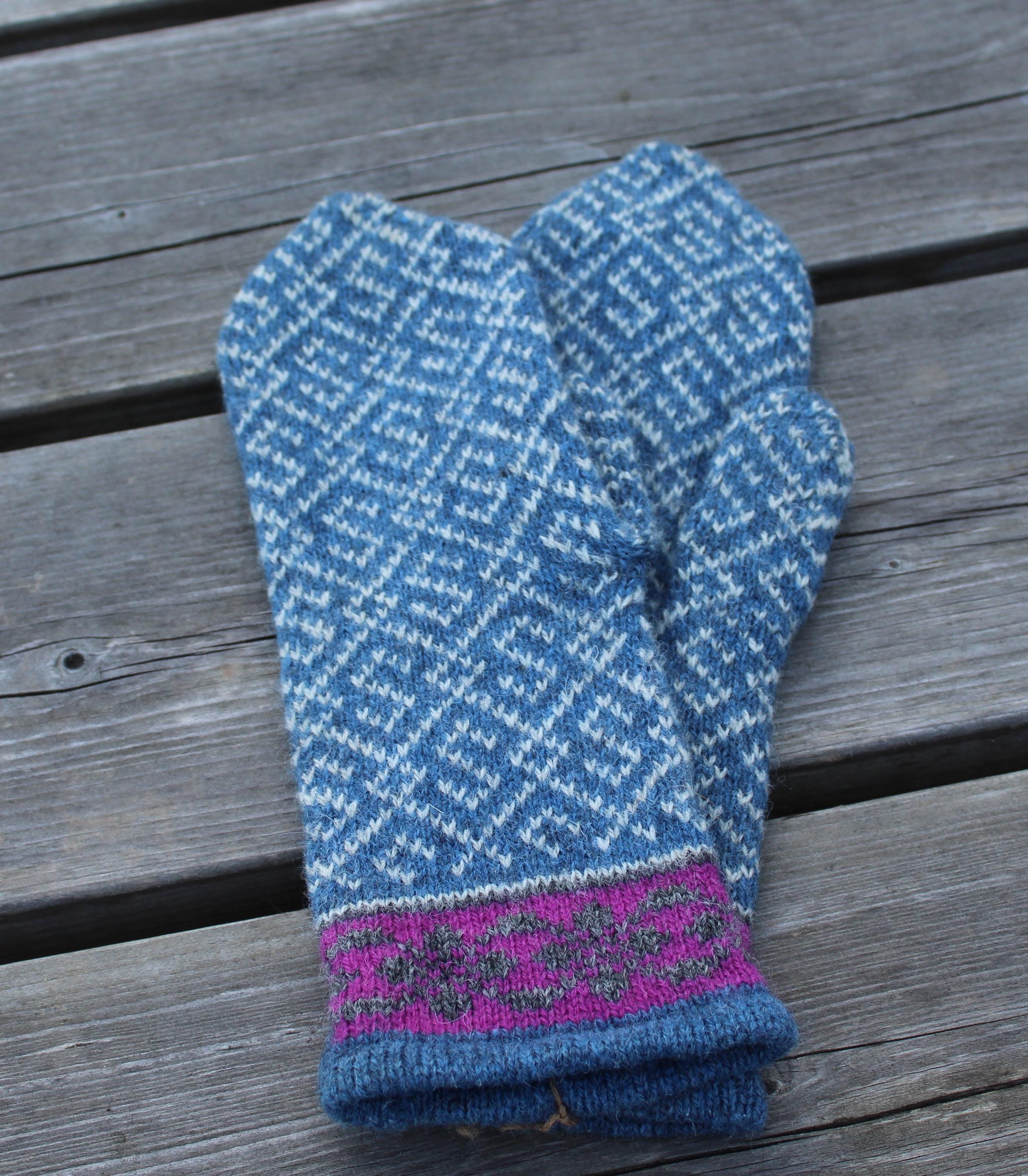 Blue knitted mittens with a purple cuff on a wooden surface