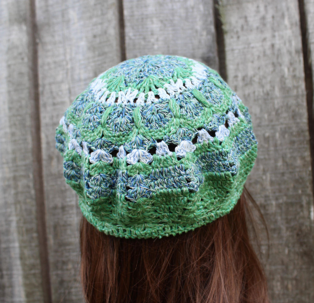 Green and white crocheted hat on a person with a wooden background