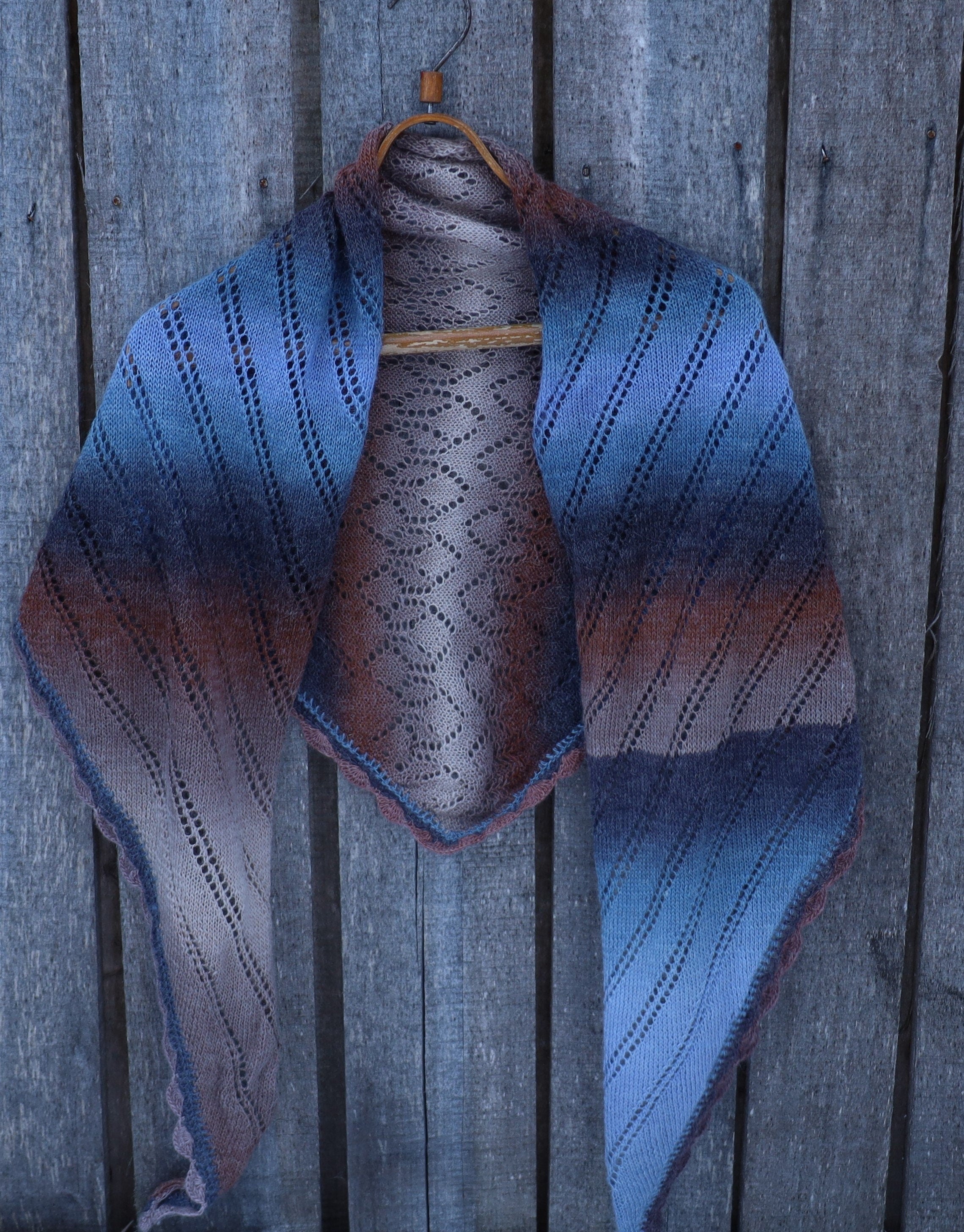 Knitted shawl with blue and brown gradient on a wooden background