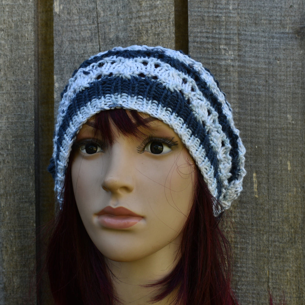 Mannequin head wearing a striped crochet hat against a wooden background