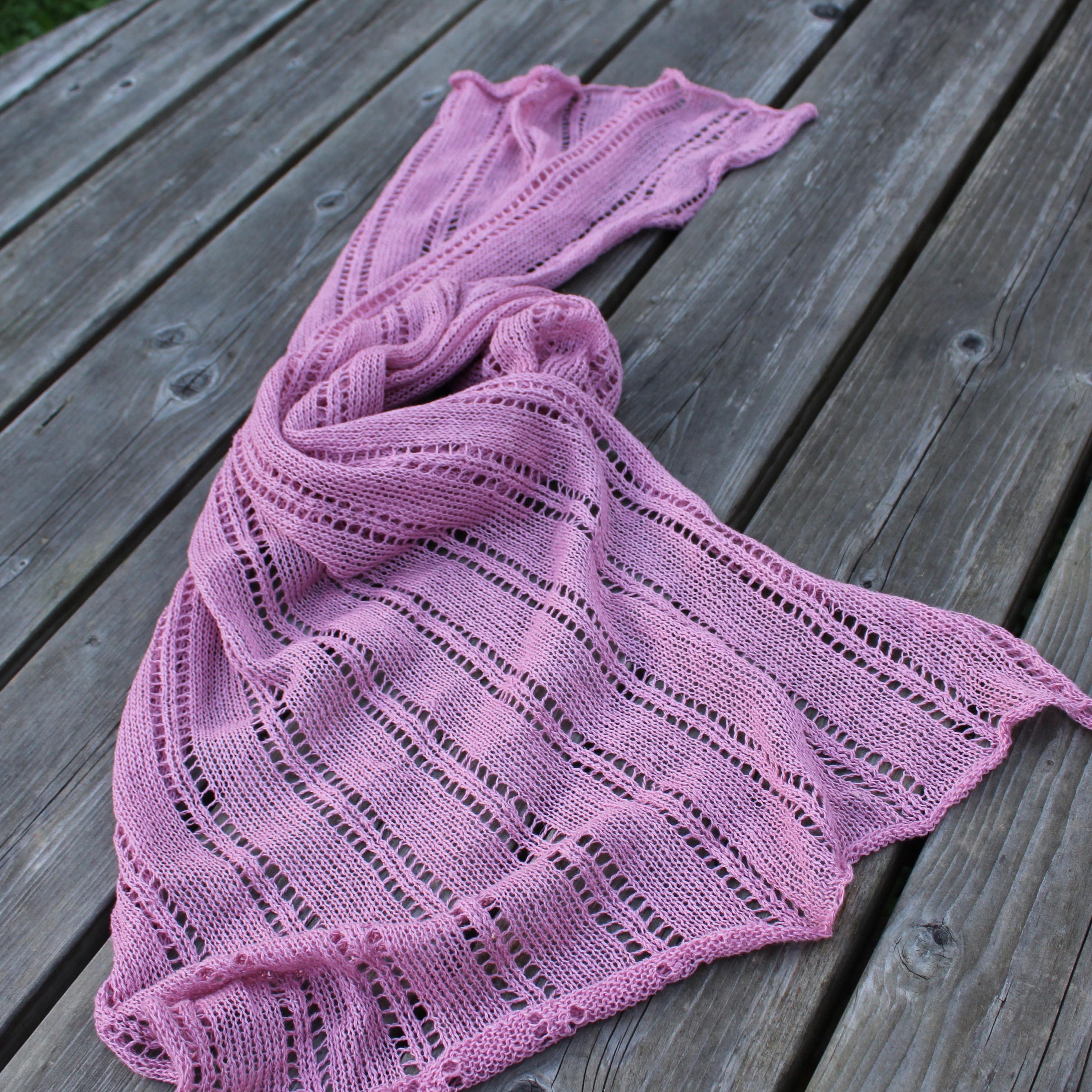 Pink knitted shawl on a wooden surface