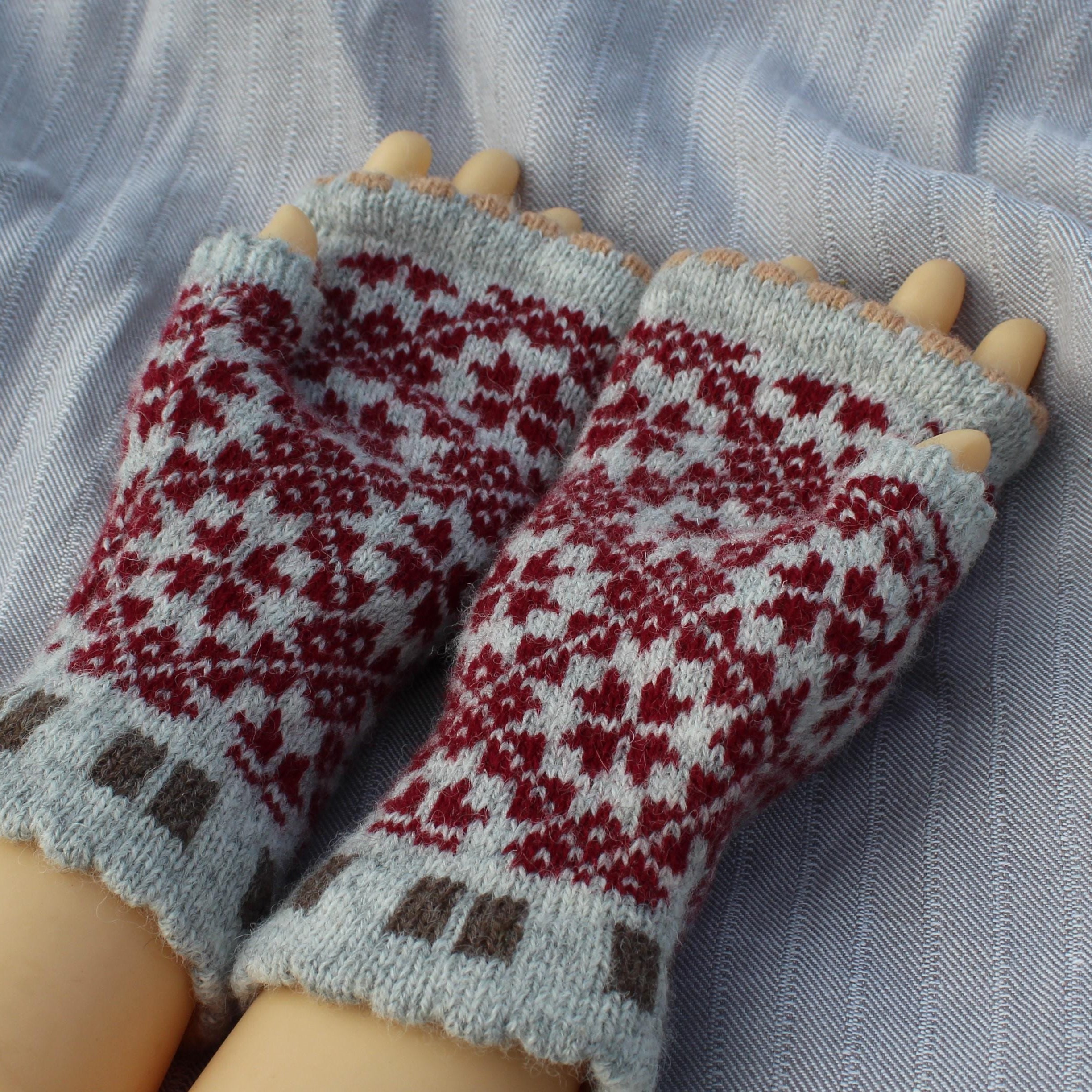 Knitted mittens with a red and white pattern on a light blue fabric background