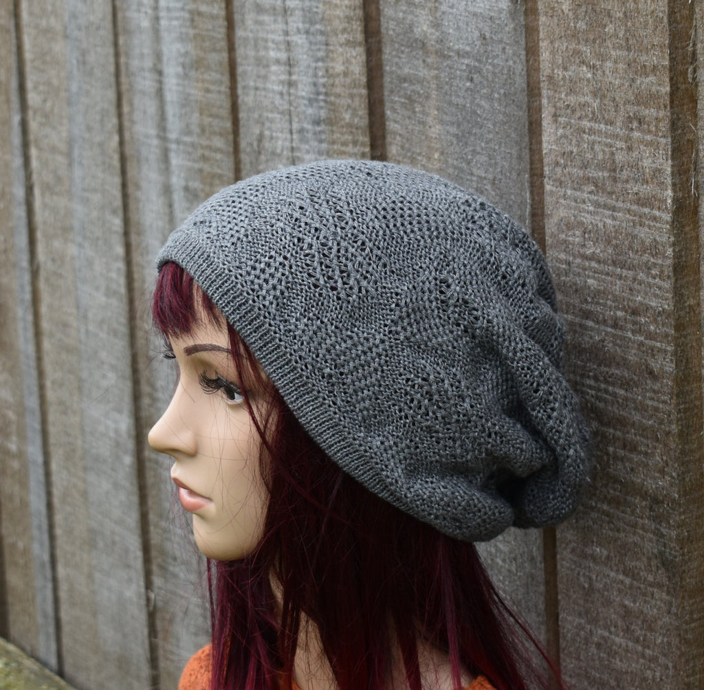 Mannequin head wearing a gray knit beanie against a wooden fence.