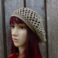 Mannequin head wearing a beige crochet hat against a wooden background