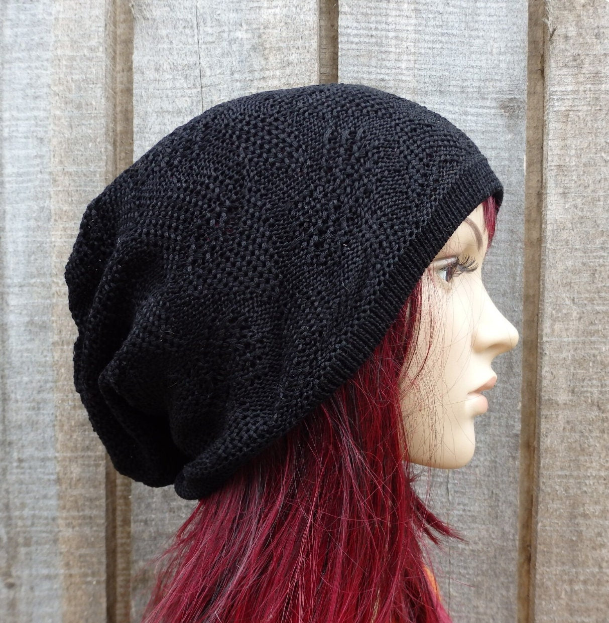 Black knit beanie on a mannequin head with red hair against a wooden background