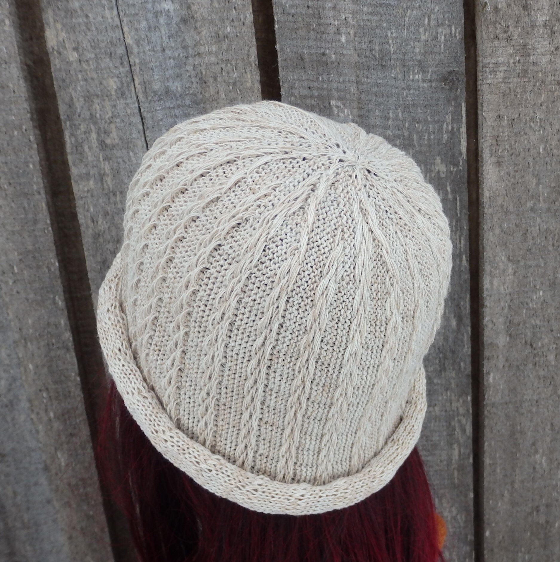 Knitted beige hat with a textured pattern on a wooden background