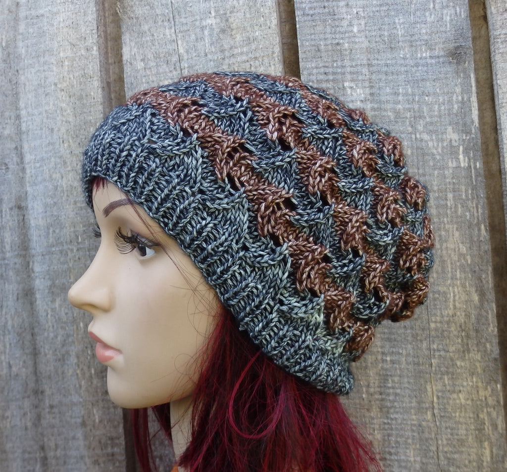 Knitted beanie in gray and brown on a mannequin head against a wooden background