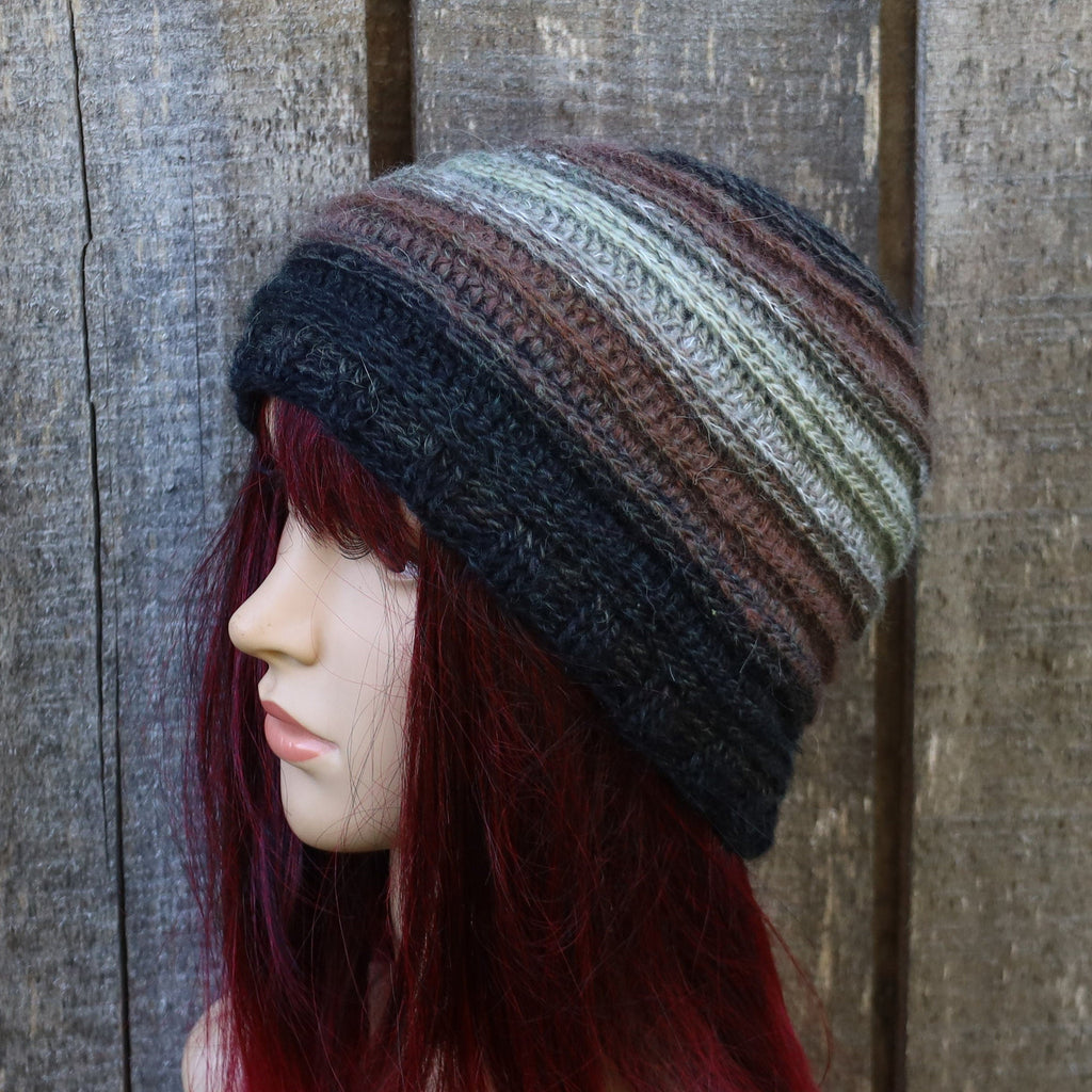 Mannequin head wearing a striped beanie against a wooden background