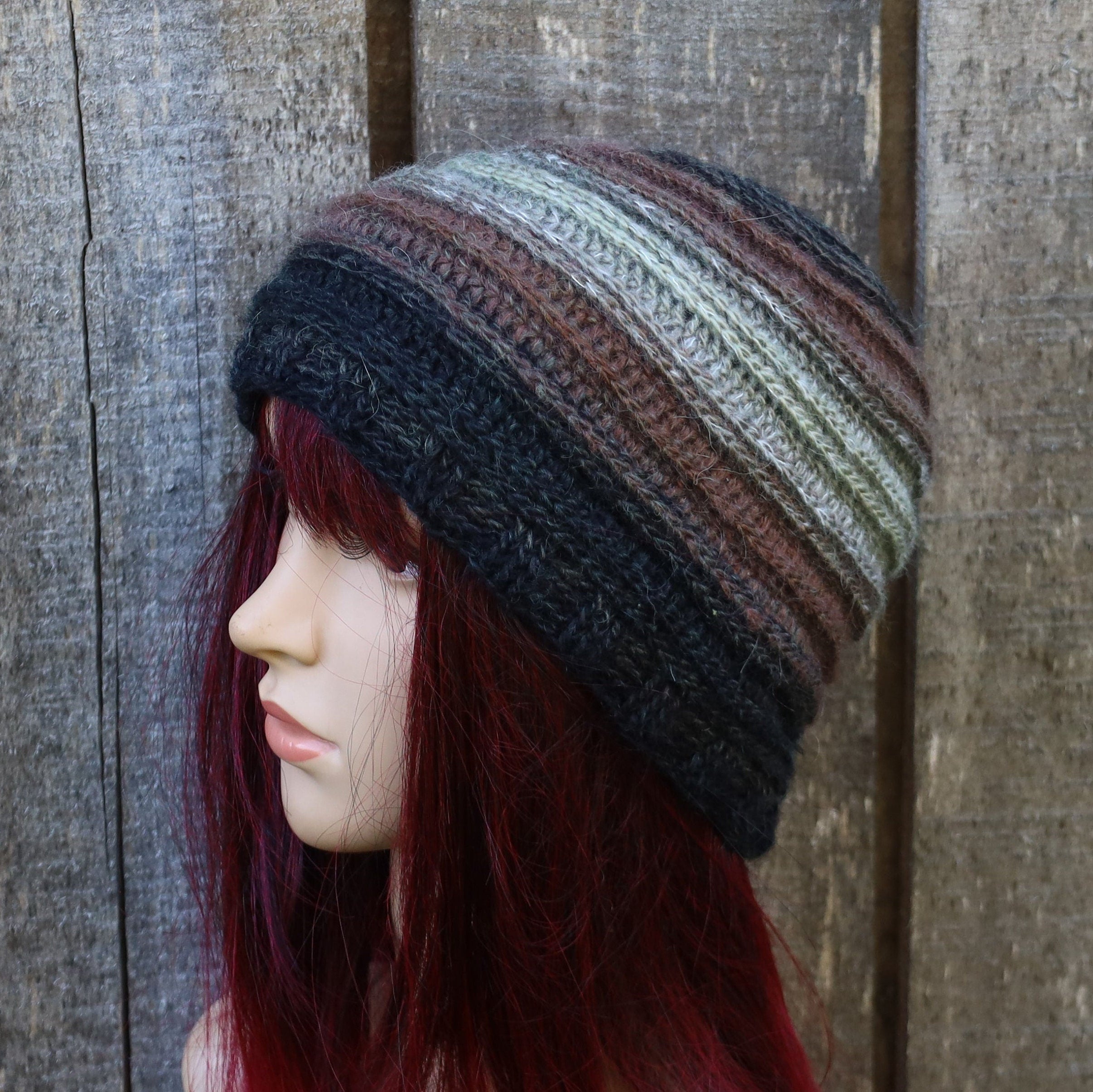 Mannequin head wearing a striped beanie against a wooden background
