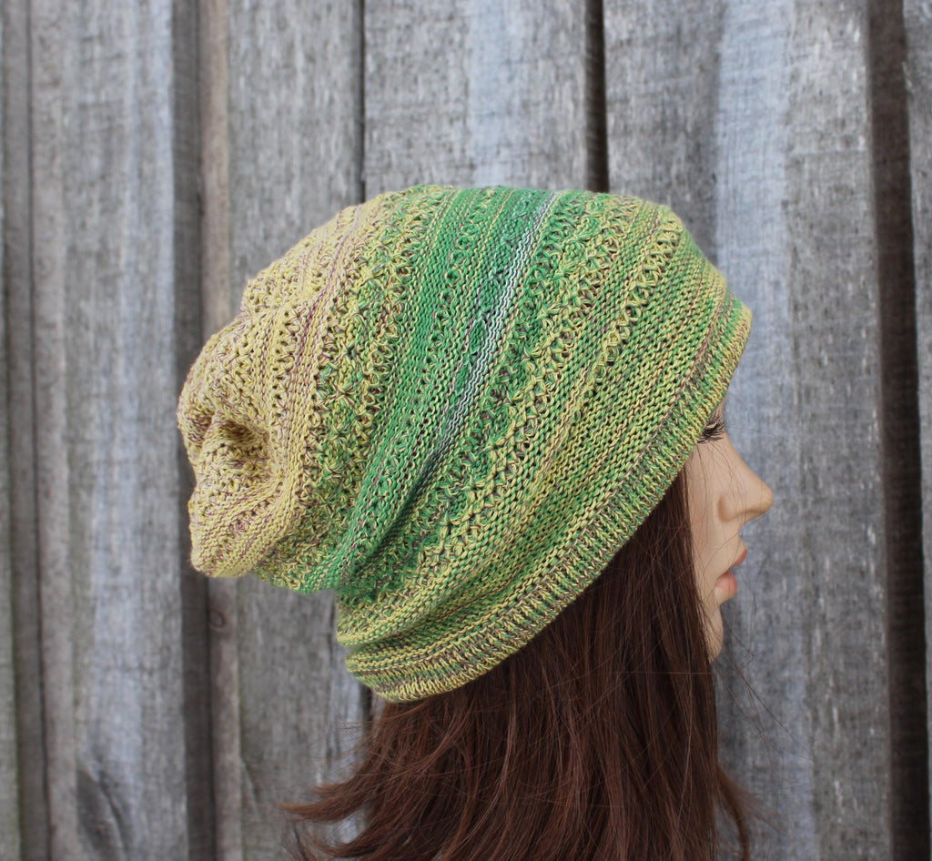 Knitted green and beige hat worn by a mannequin against a wooden background