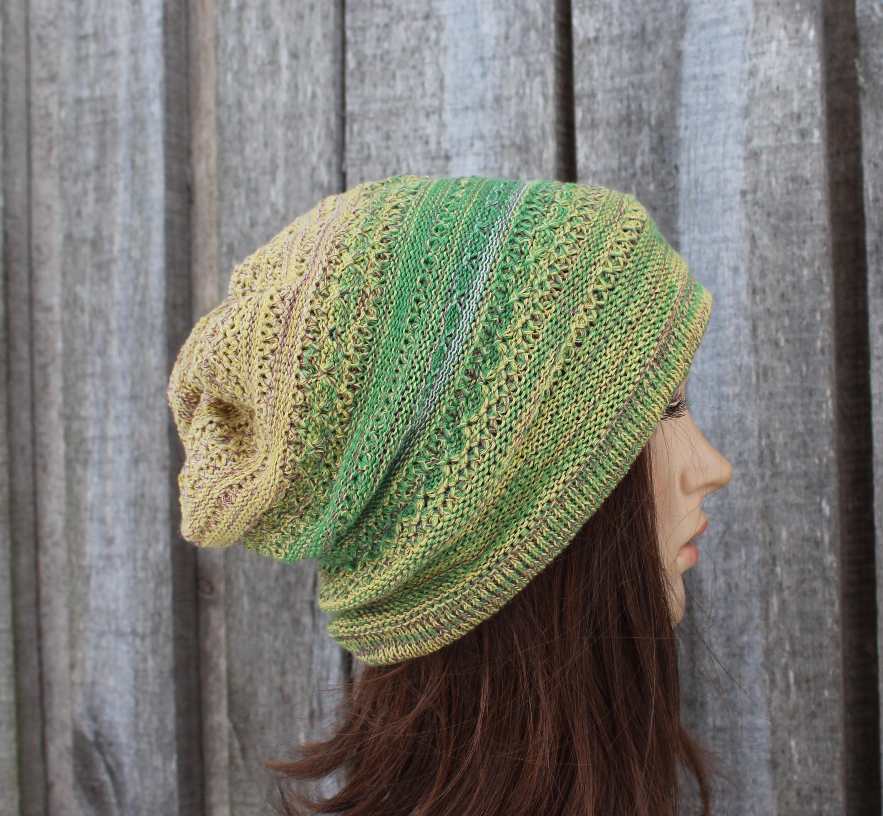 Knitted green and beige hat worn by a mannequin against a wooden background