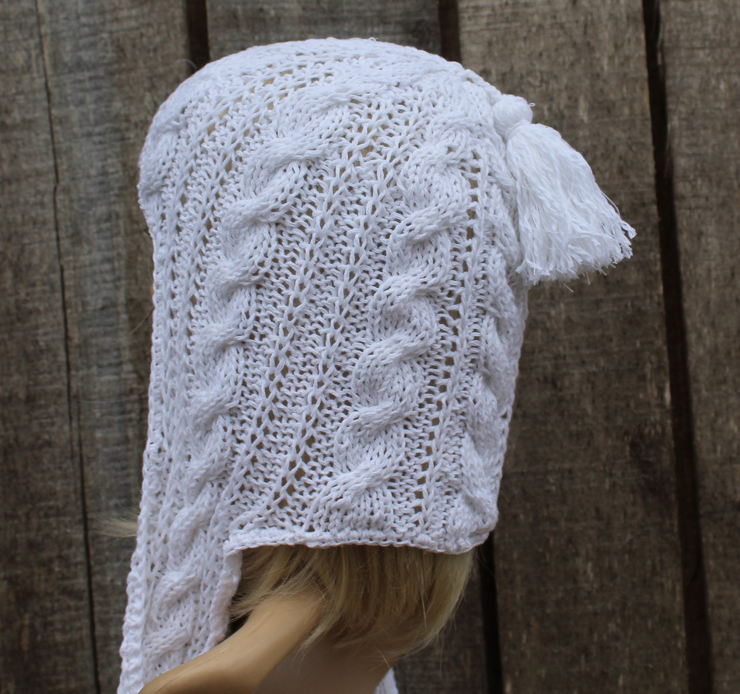 White knitted hood on a mannequin head against a wooden background