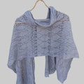 Knitted shawl on a wooden hanger against a wooden background