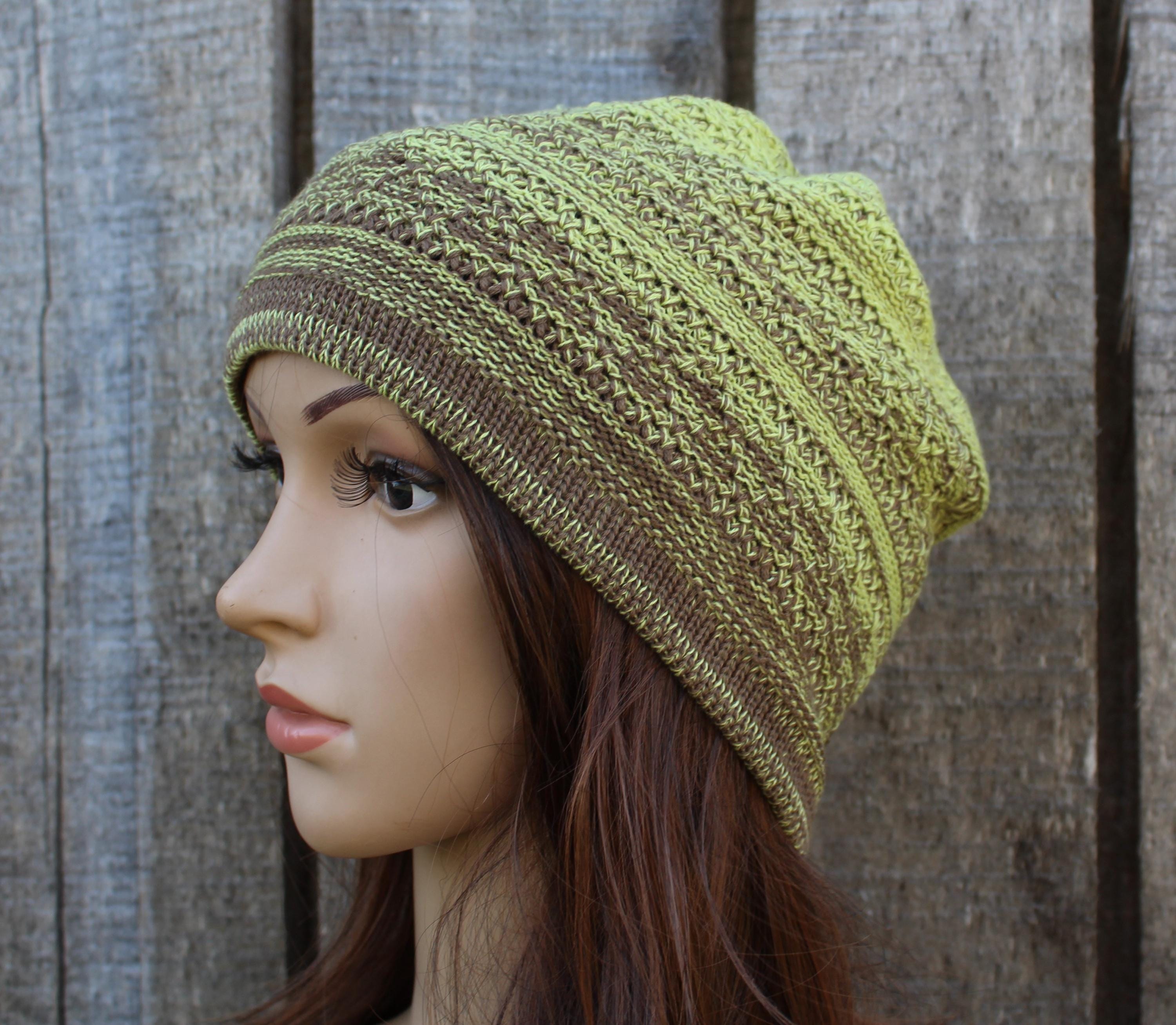 Knitted green and brown beanie on a mannequin head against a wooden background