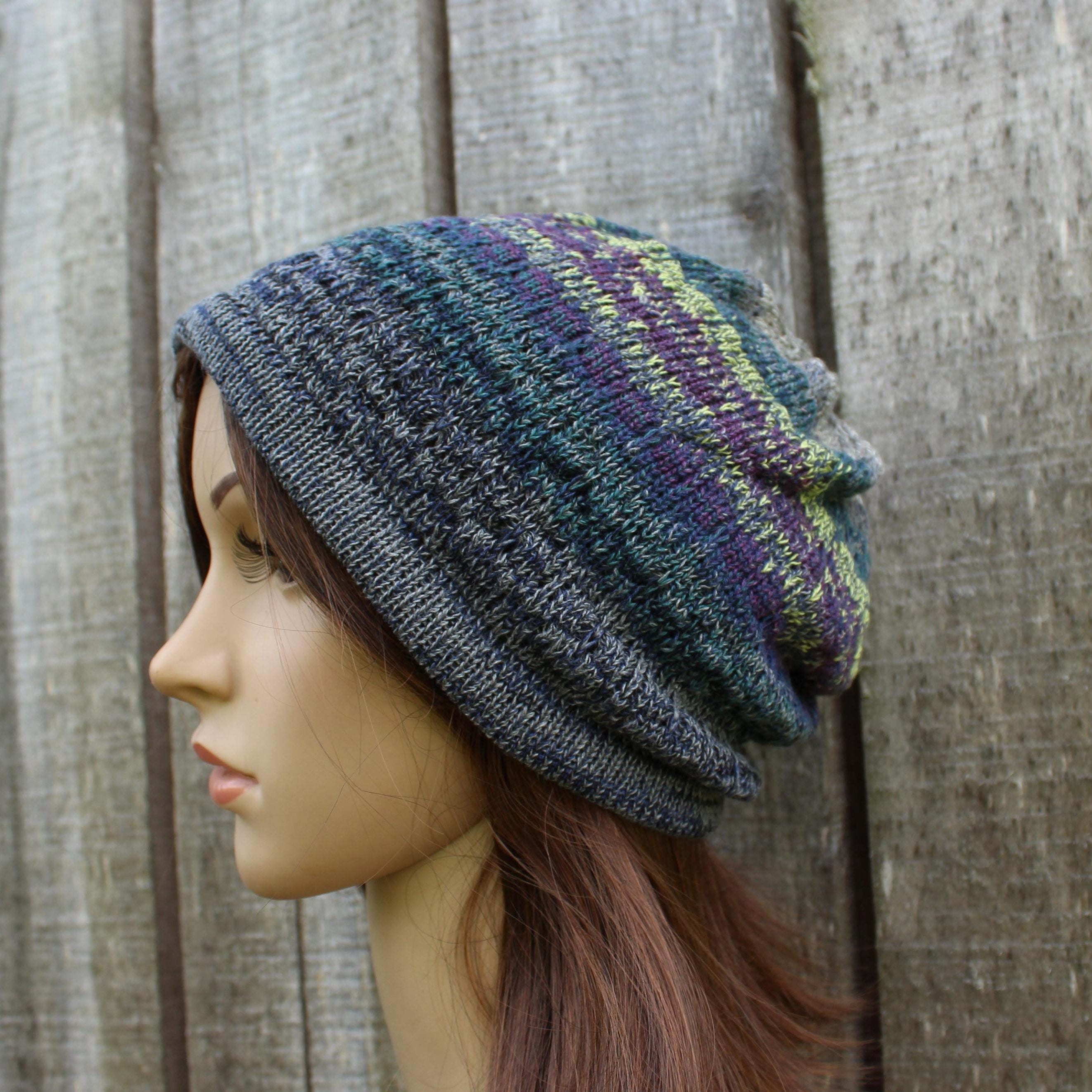 Mannequin head wearing a knitted multicolored beanie against a wooden background