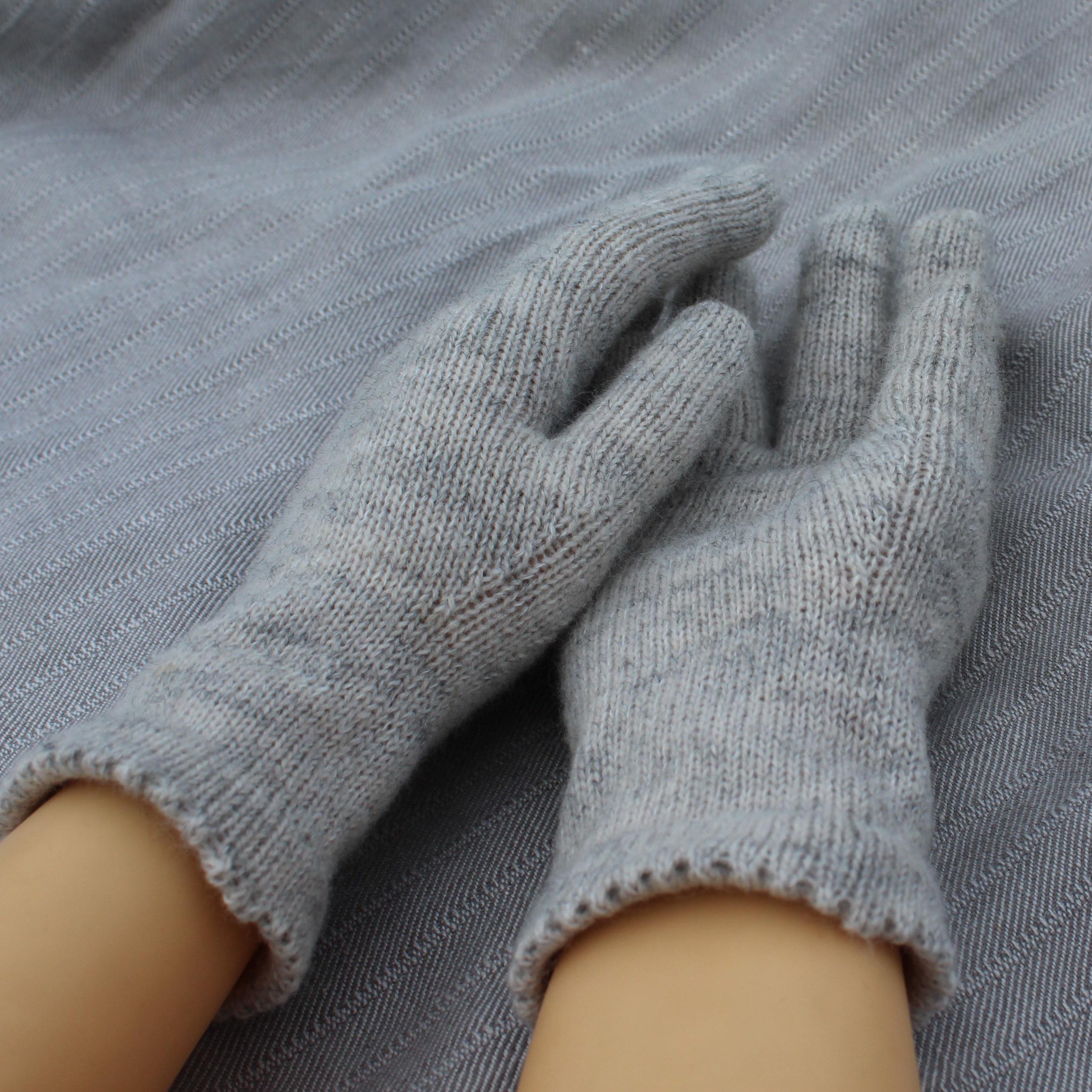 Gray gloves on a person's hands against a gray fabric background