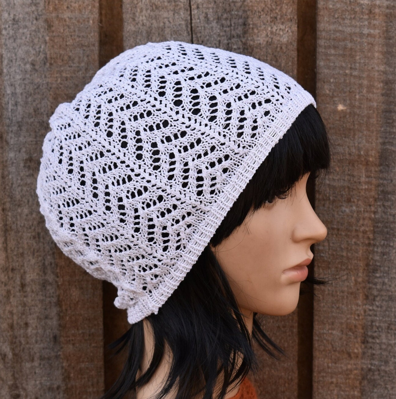White lace knit hat on a mannequin head against a wooden background