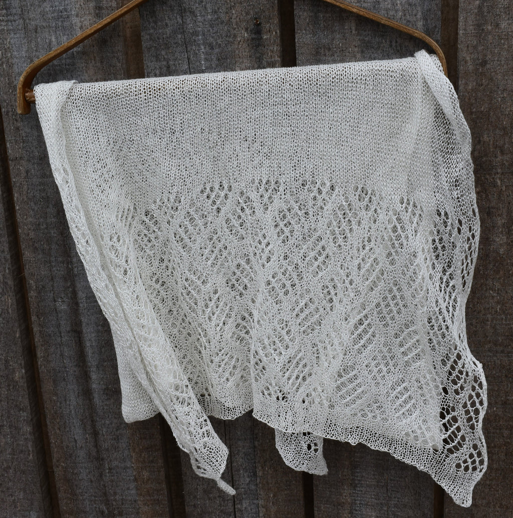 Knitted lace shawl hanging on a wooden surface