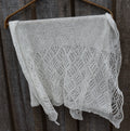 Knitted lace shawl hanging on a wooden surface
