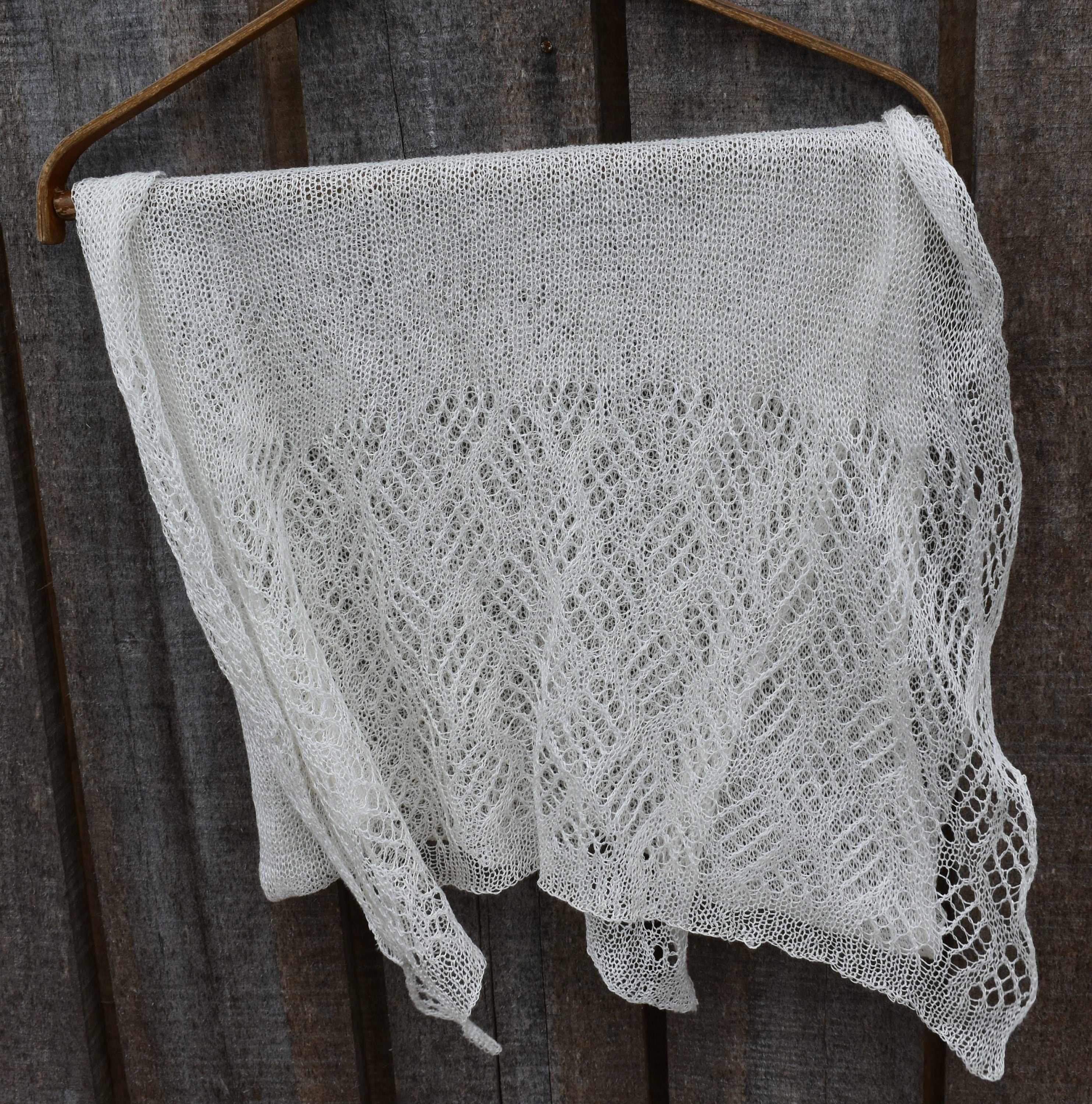 Knitted lace shawl hanging on a wooden surface