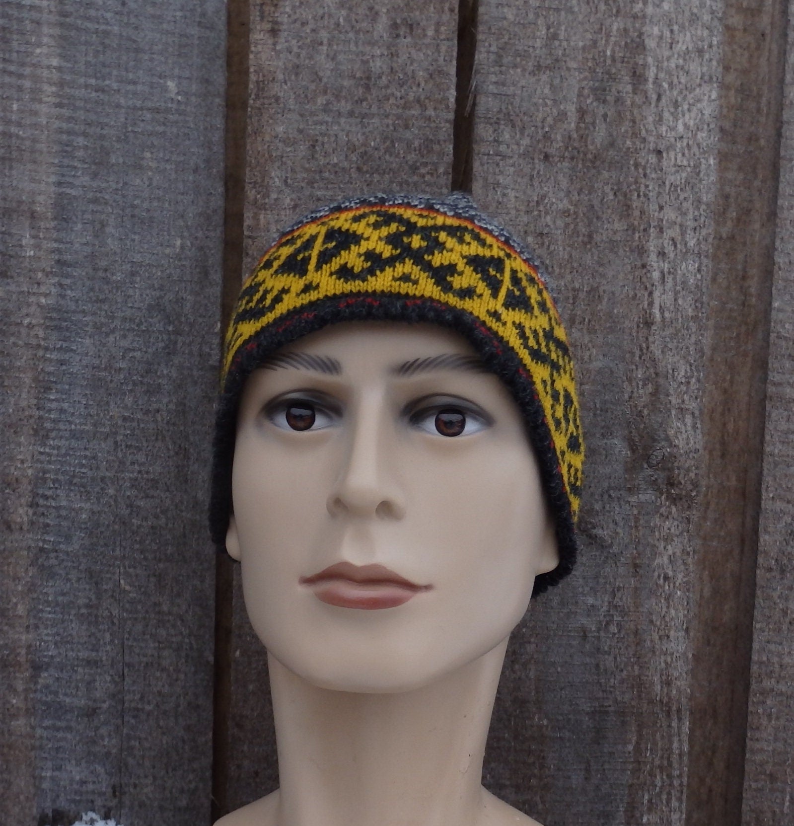 Mannequin head wearing a patterned beanie against a wooden background