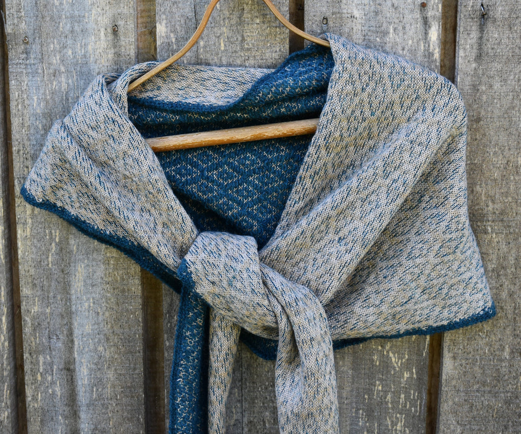 Textured blue and gray scarf on a wooden hanger against a wooden background