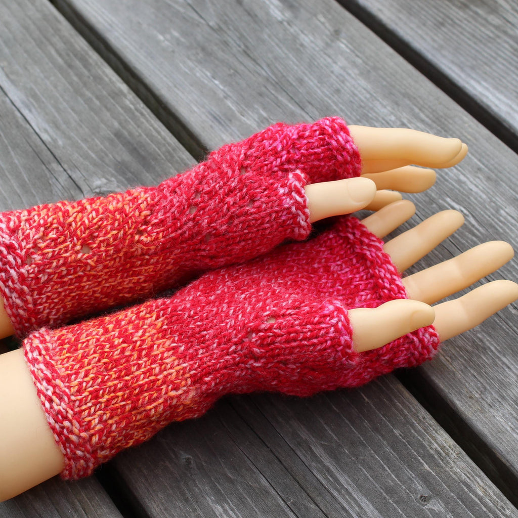Red knitted fingerless gloves on a mannequin hand against a wooden background