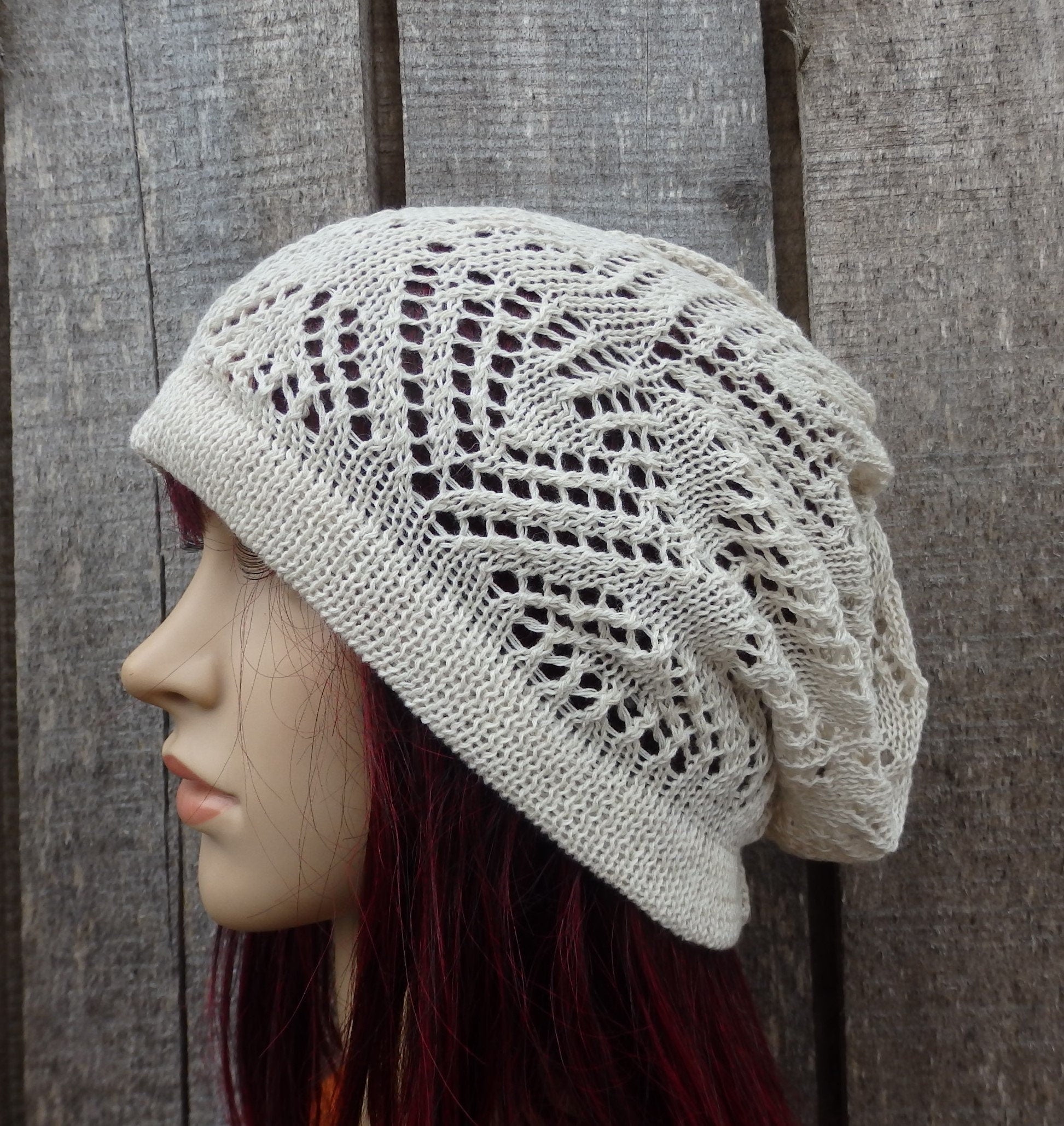 Knitted lace hat on a mannequin head against a wooden background