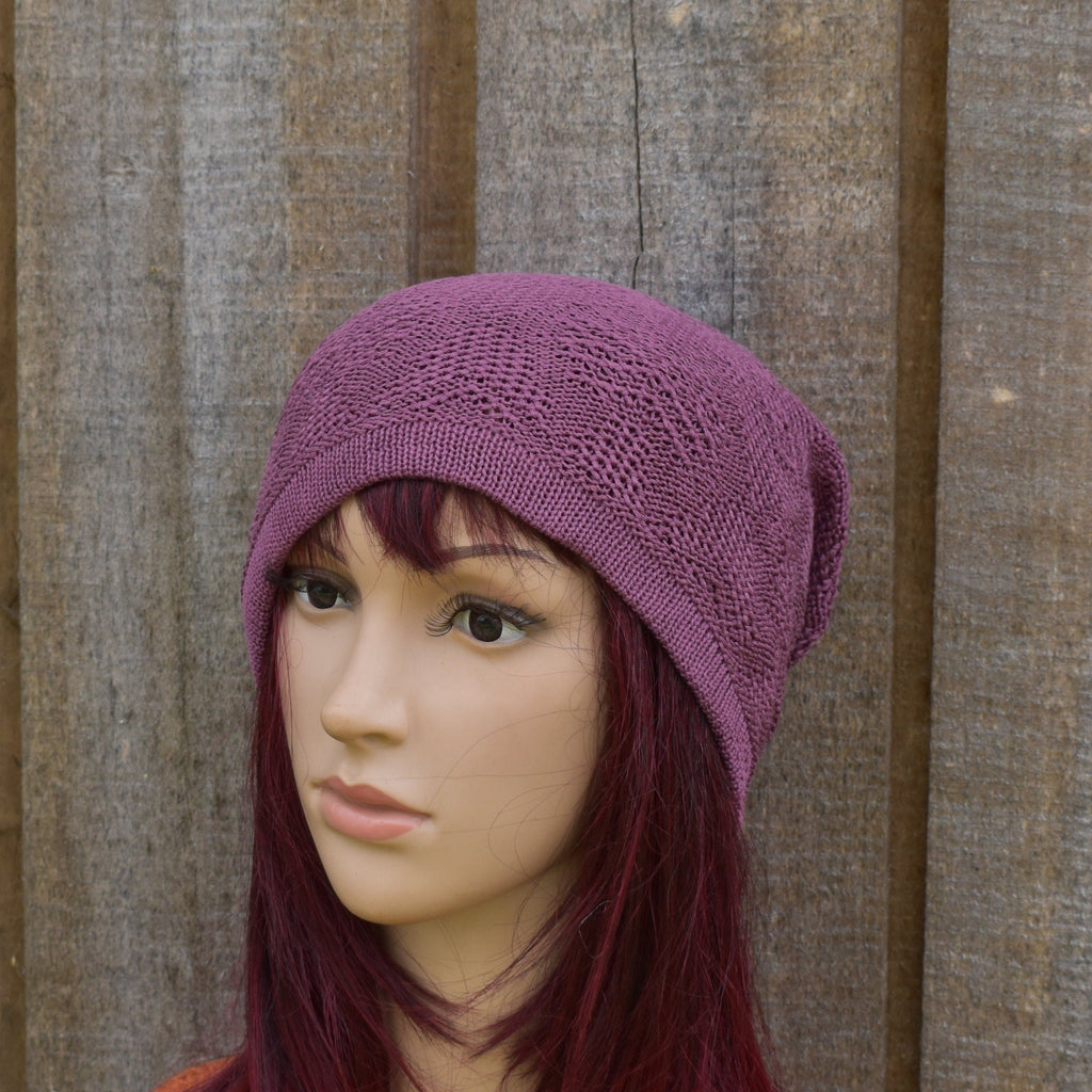 Mannequin head wearing a purple knitted hat against a wooden background