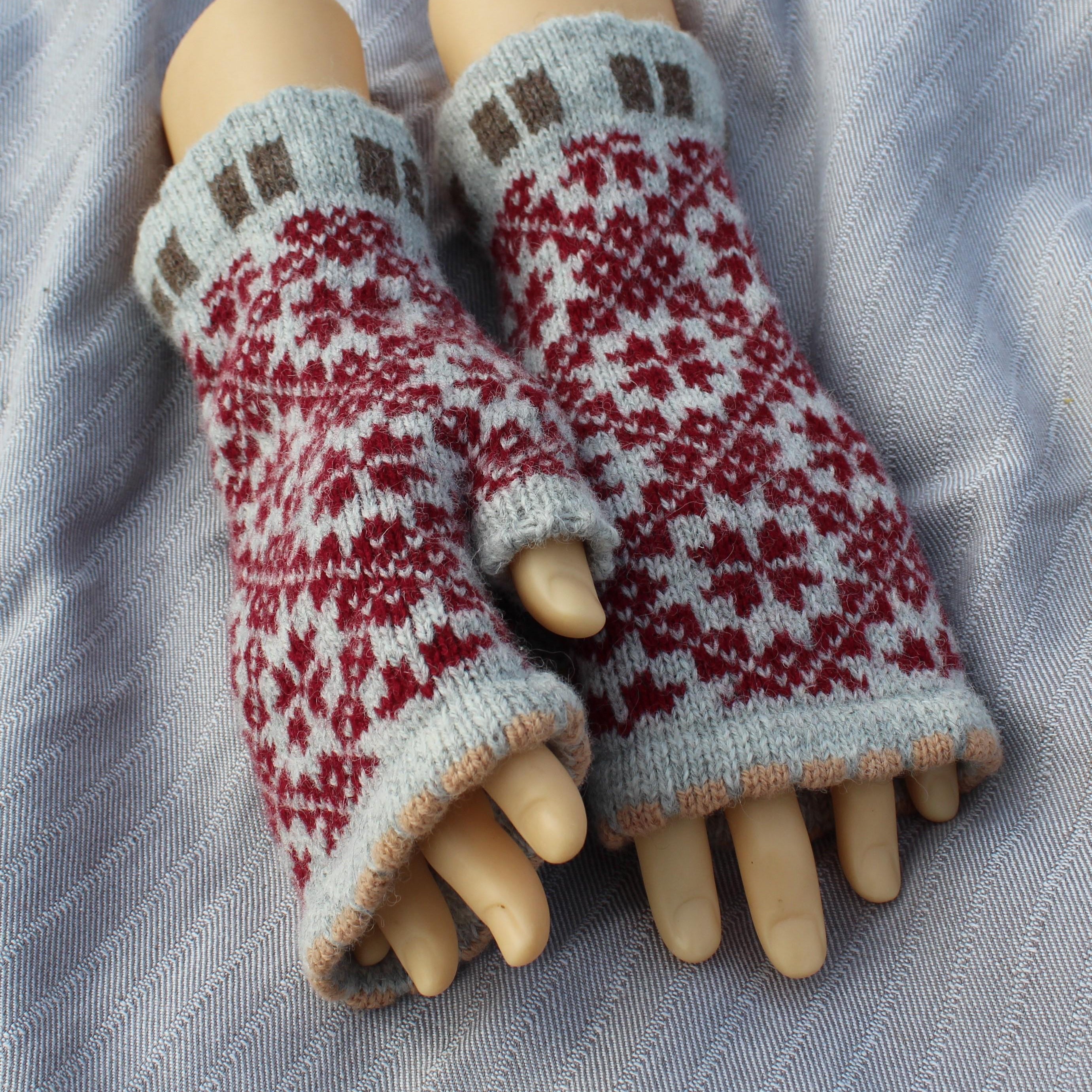 Pair of knitted fingerless gloves with a pattern on a fabric background