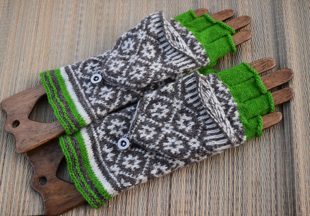 Pair of patterned gloves with green cuffs and wooden handles on a wooden surface