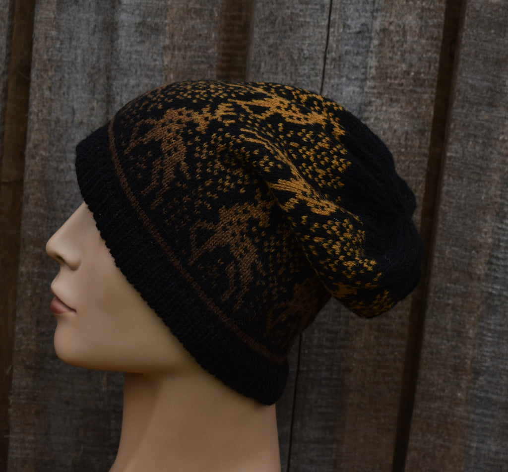 Knitted beanie with black and gold pattern on a mannequin head against a textured brown background