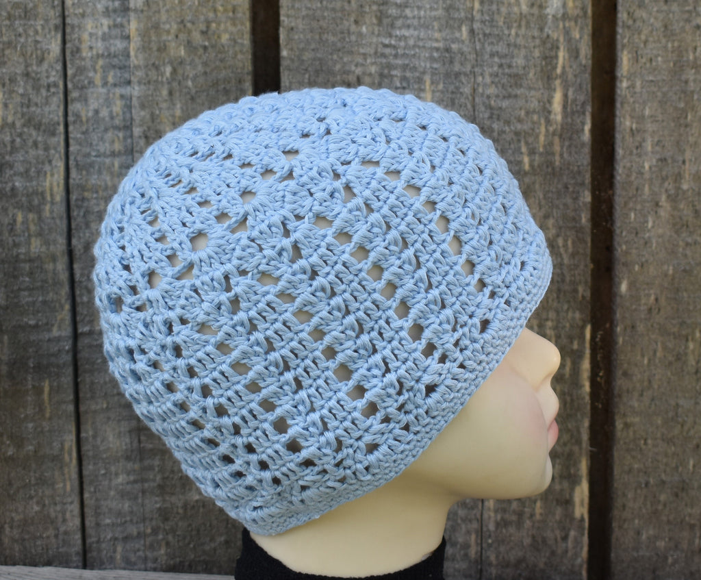 Blue crochet beanie on a mannequin head against a wooden background