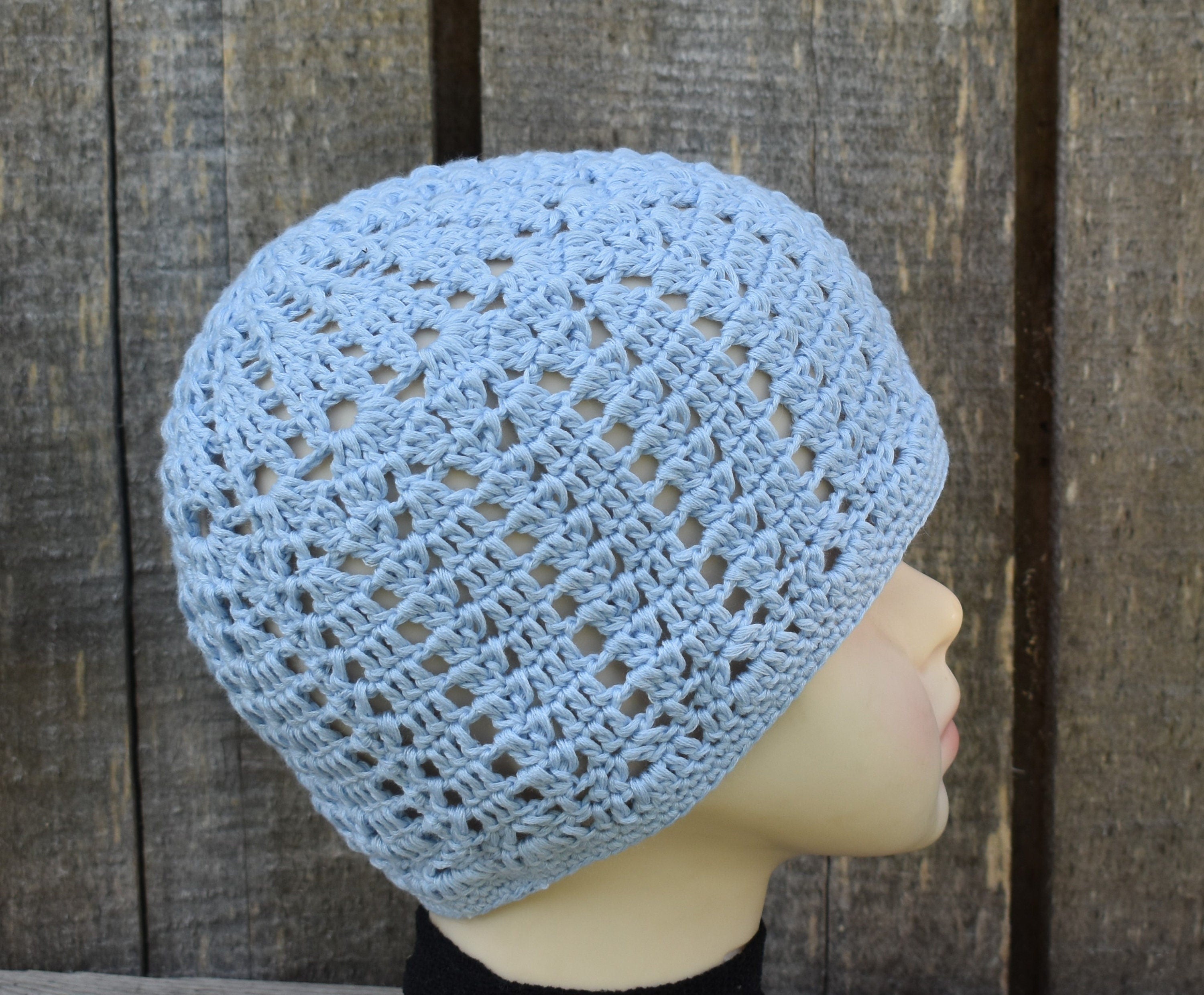 Blue crochet beanie on a mannequin head against a wooden background