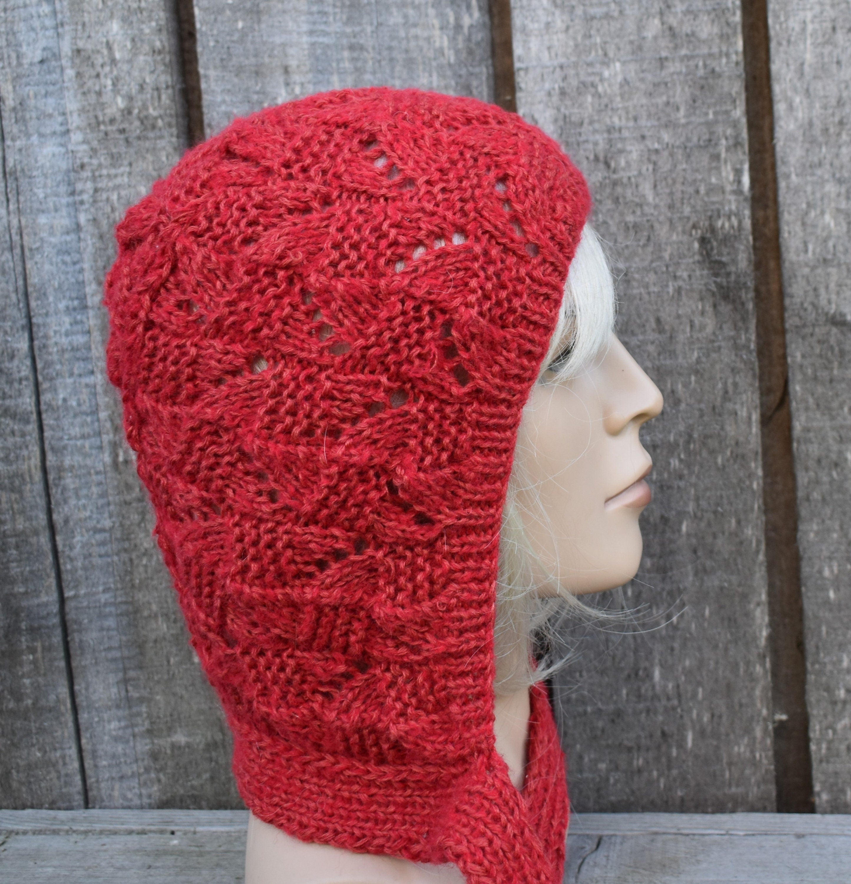 Red knitted hood worn by a mannequin against a wooden background