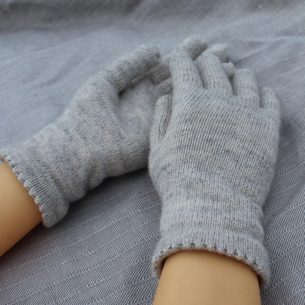 Gray gloves being worn on a gray fabric background