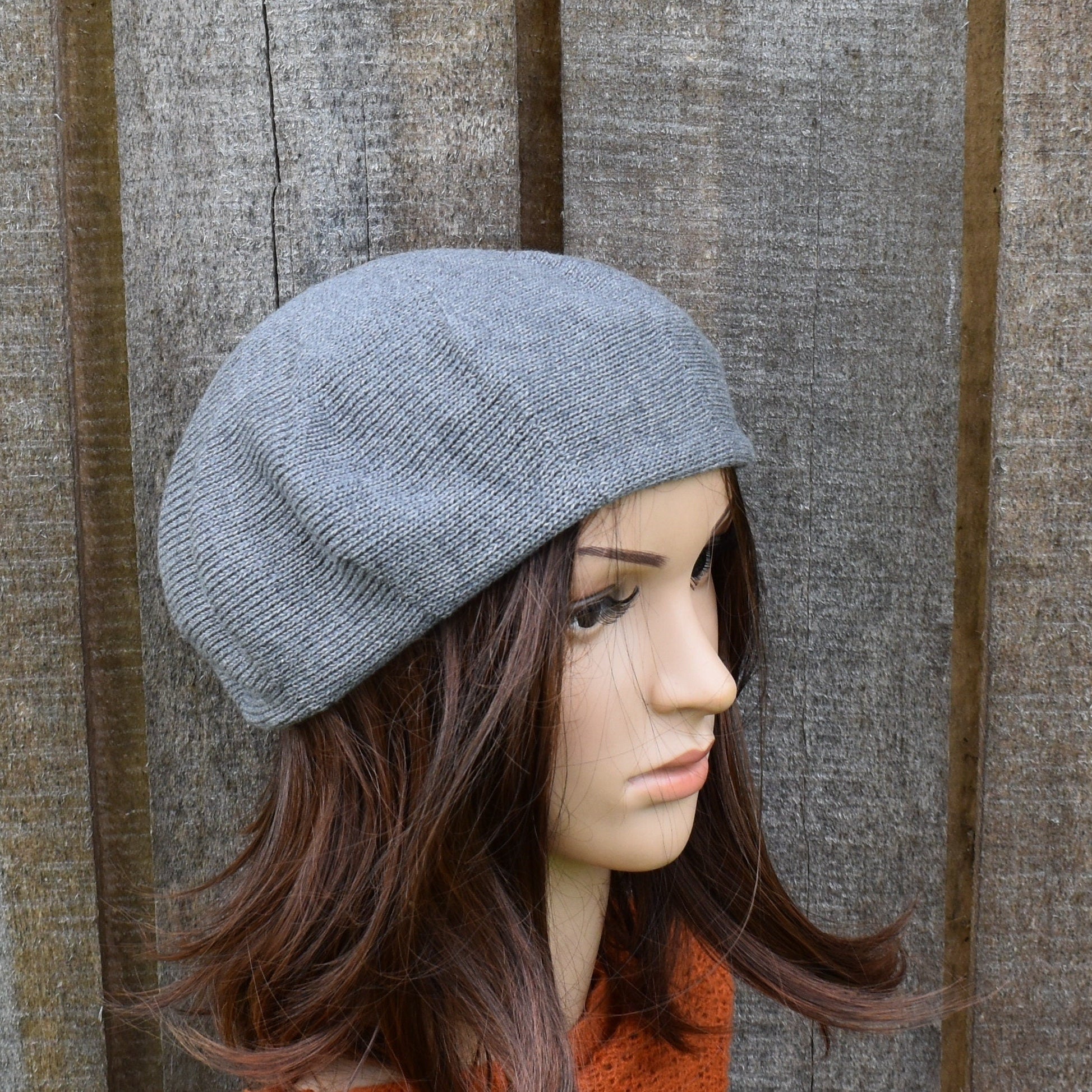 Mannequin head wearing a gray knit beanie against a wooden background