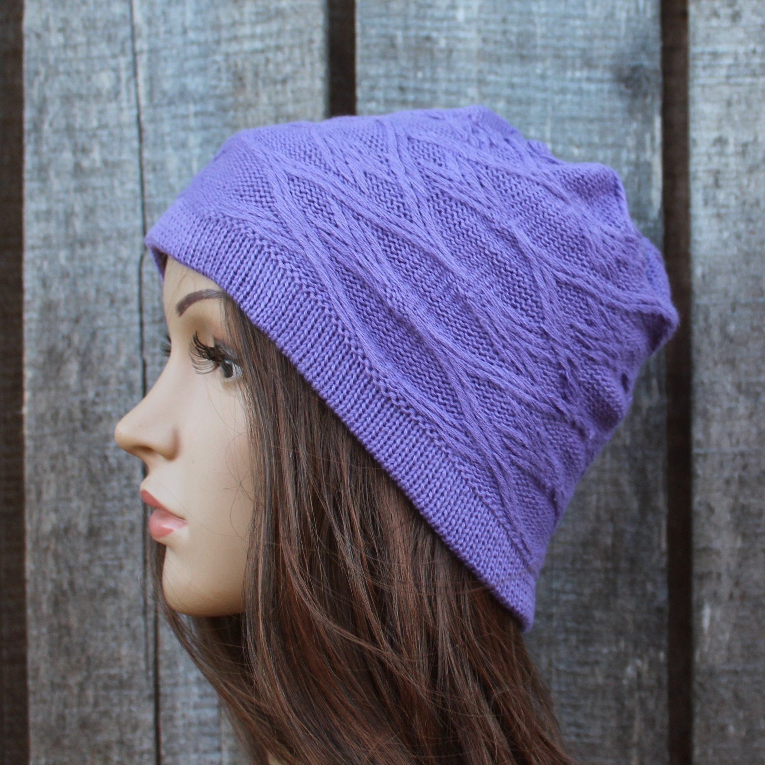 Person wearing a purple knitted beanie against a wooden background