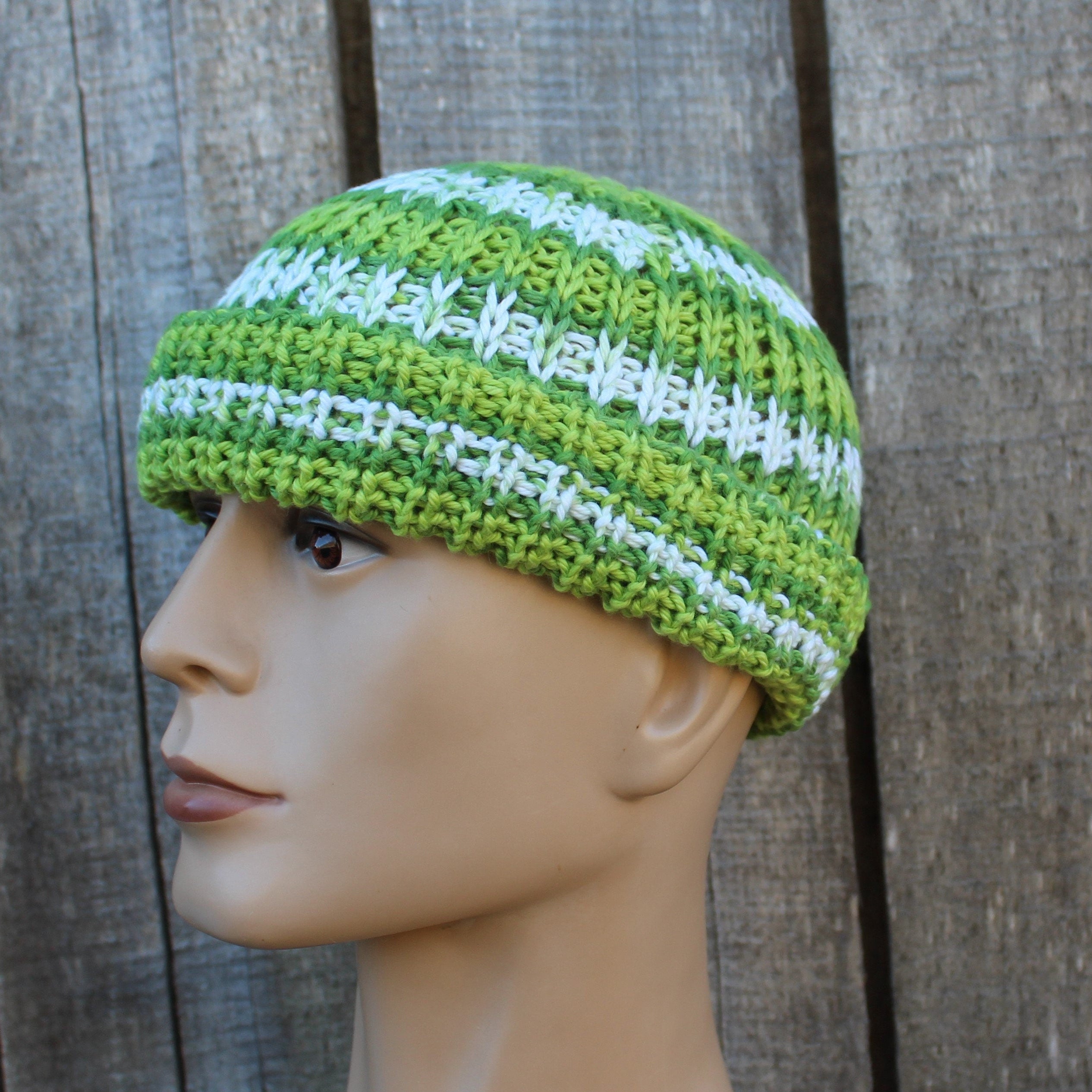 Green and white striped knit beanie on a mannequin head against a wooden background