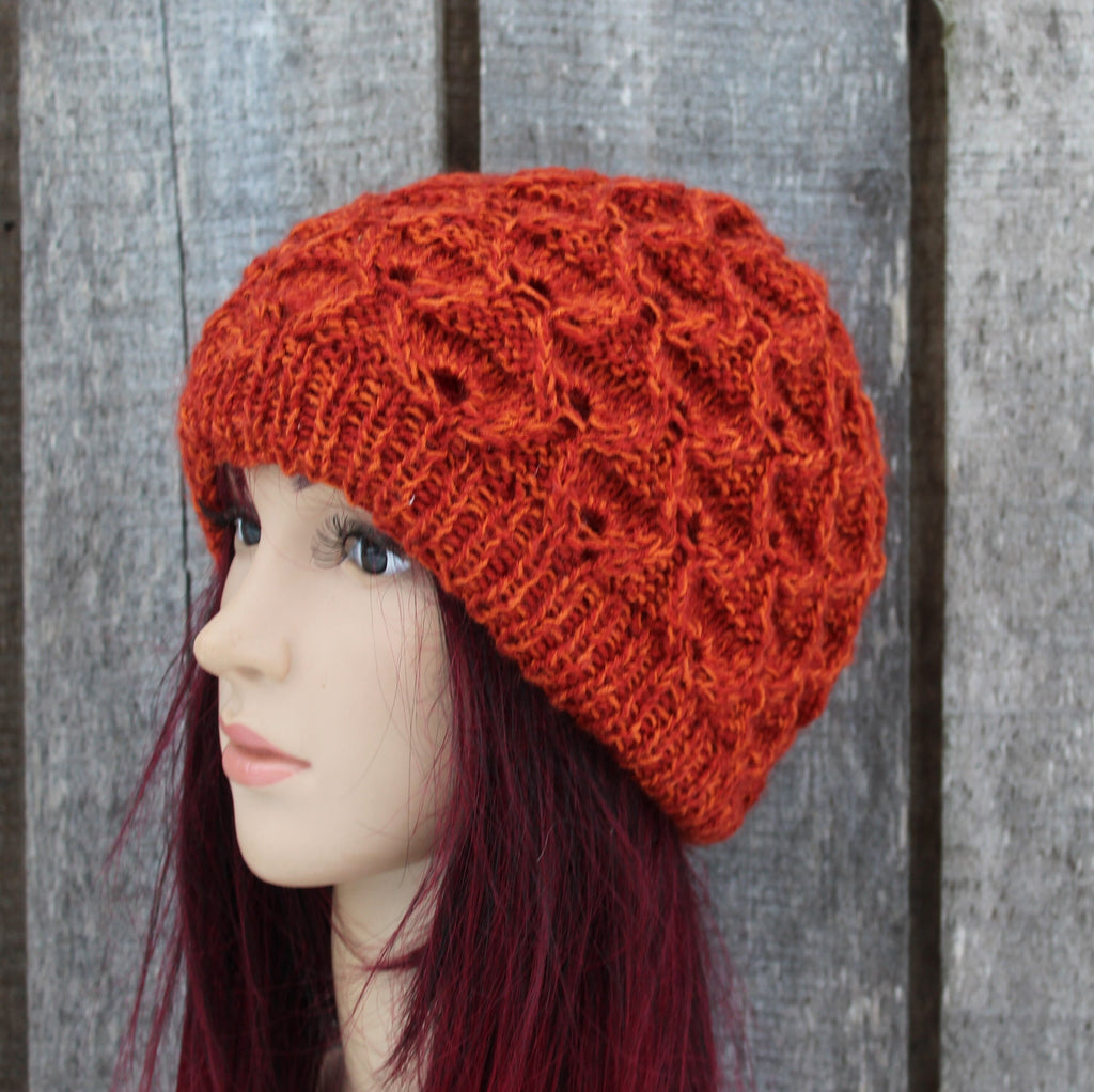 Mannequin head wearing a red knitted hat against a wooden background