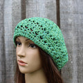 Green crochet hat on a mannequin head against a wooden background