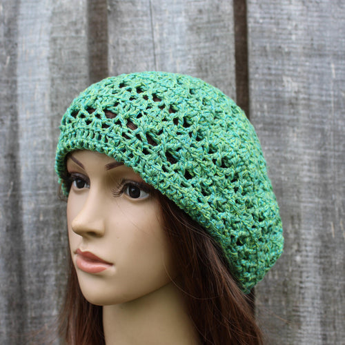 Green crochet hat on a mannequin head against a wooden background