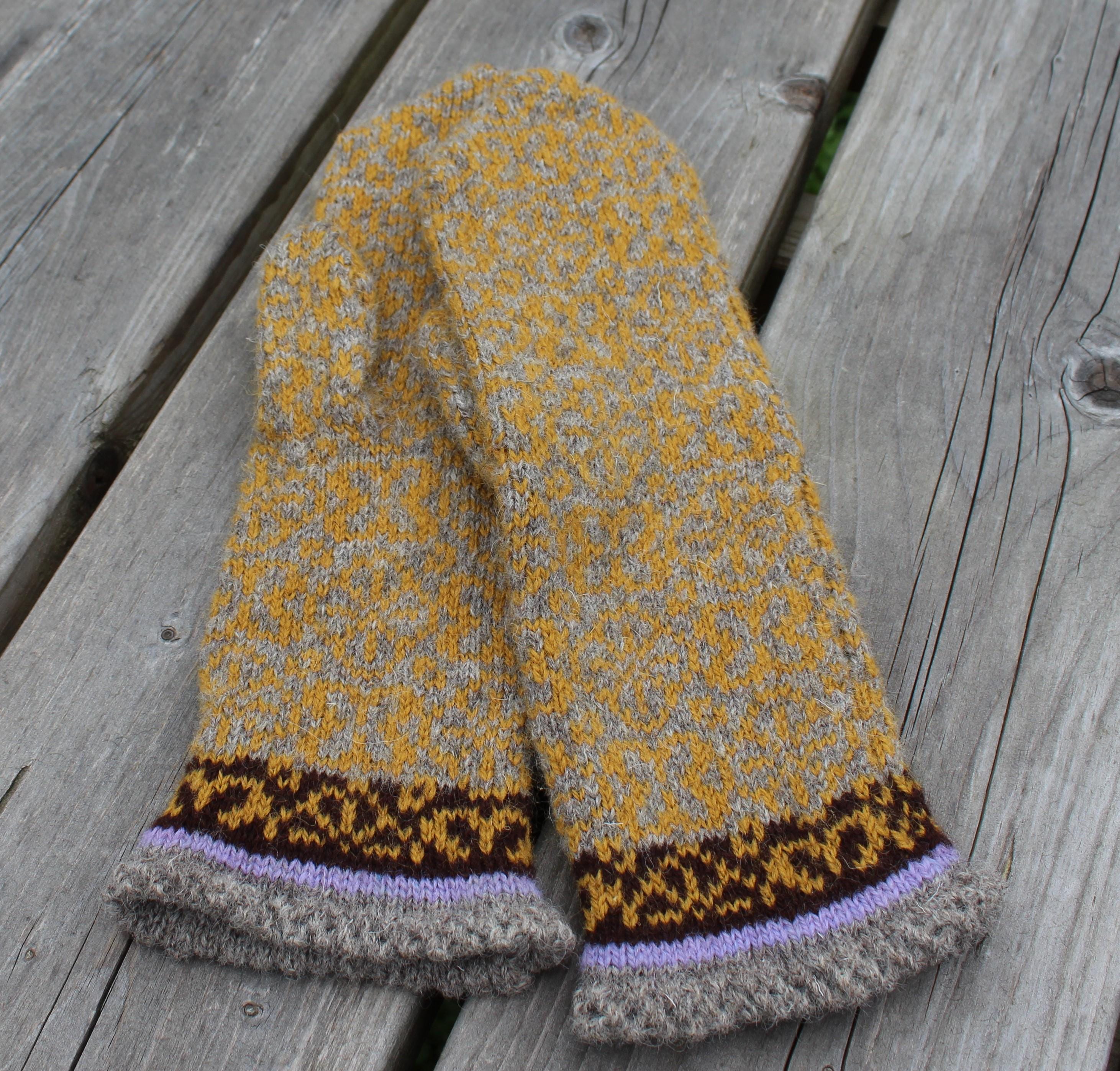 Knitted mittens with a pattern on a wooden surface