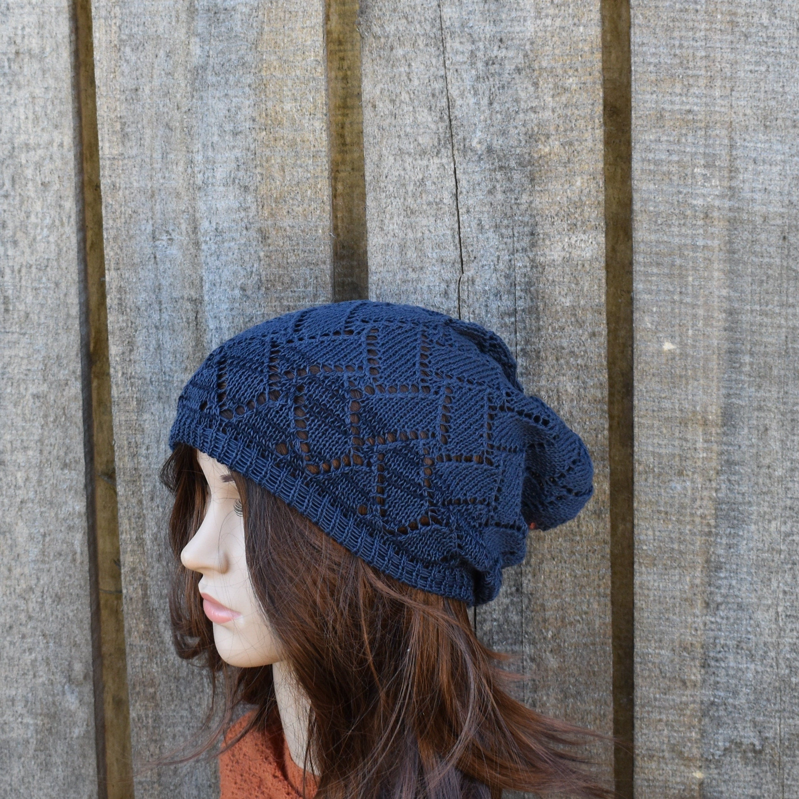 Cotton knitted hat on a mannequin head against a wooden background