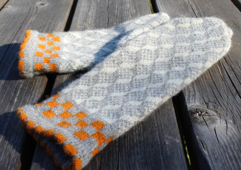 Knitted gloves with orange pattern on a wooden surface