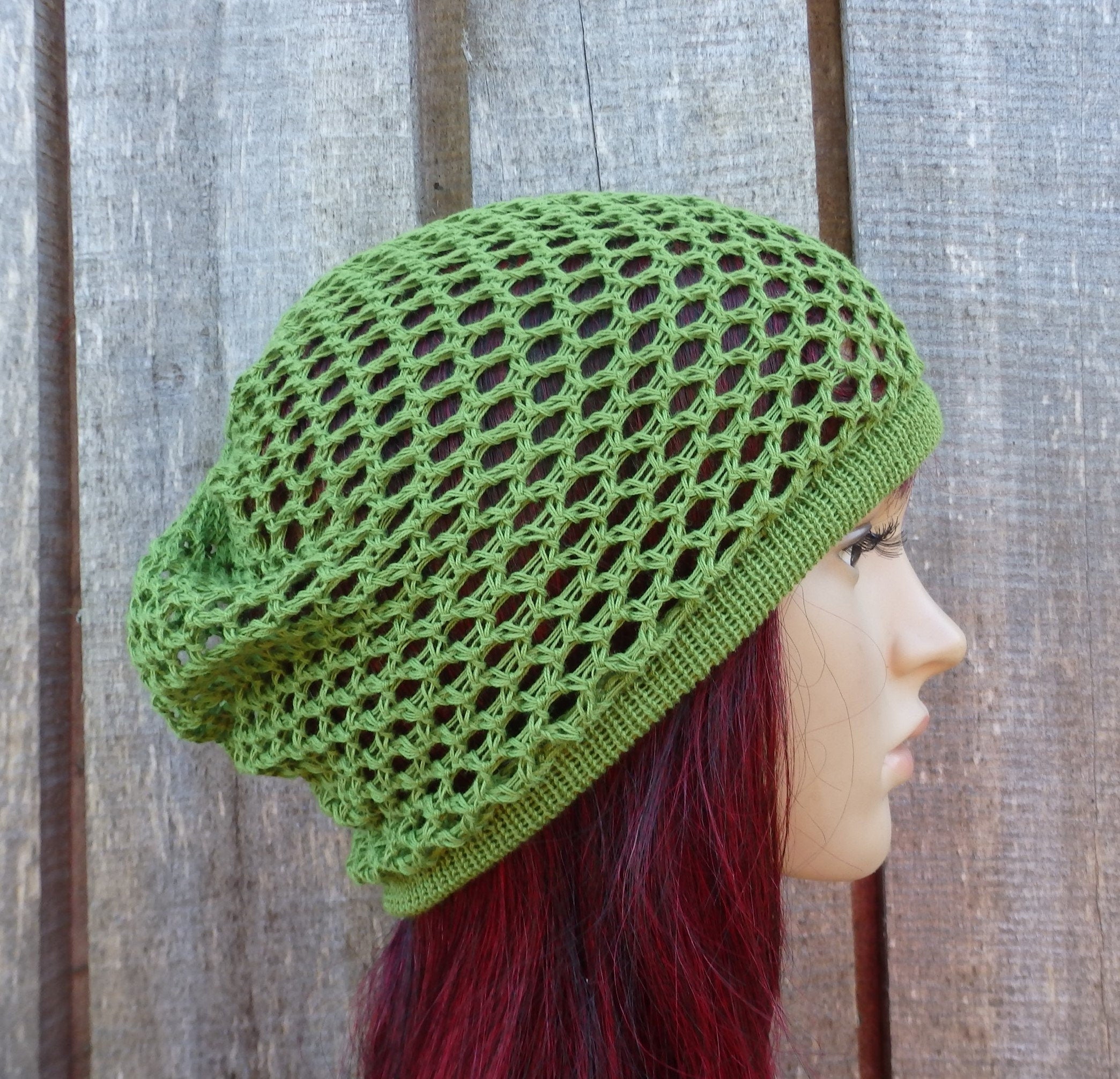 Green knitted beanie on a mannequin head against a wooden background