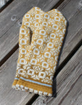 Knitted mittens with a yellow and white pattern on a wooden surface