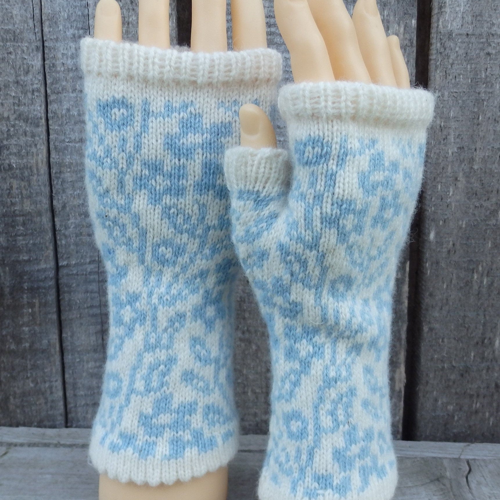 Pair of blue and white patterned fingerless gloves on a wooden mannequin.