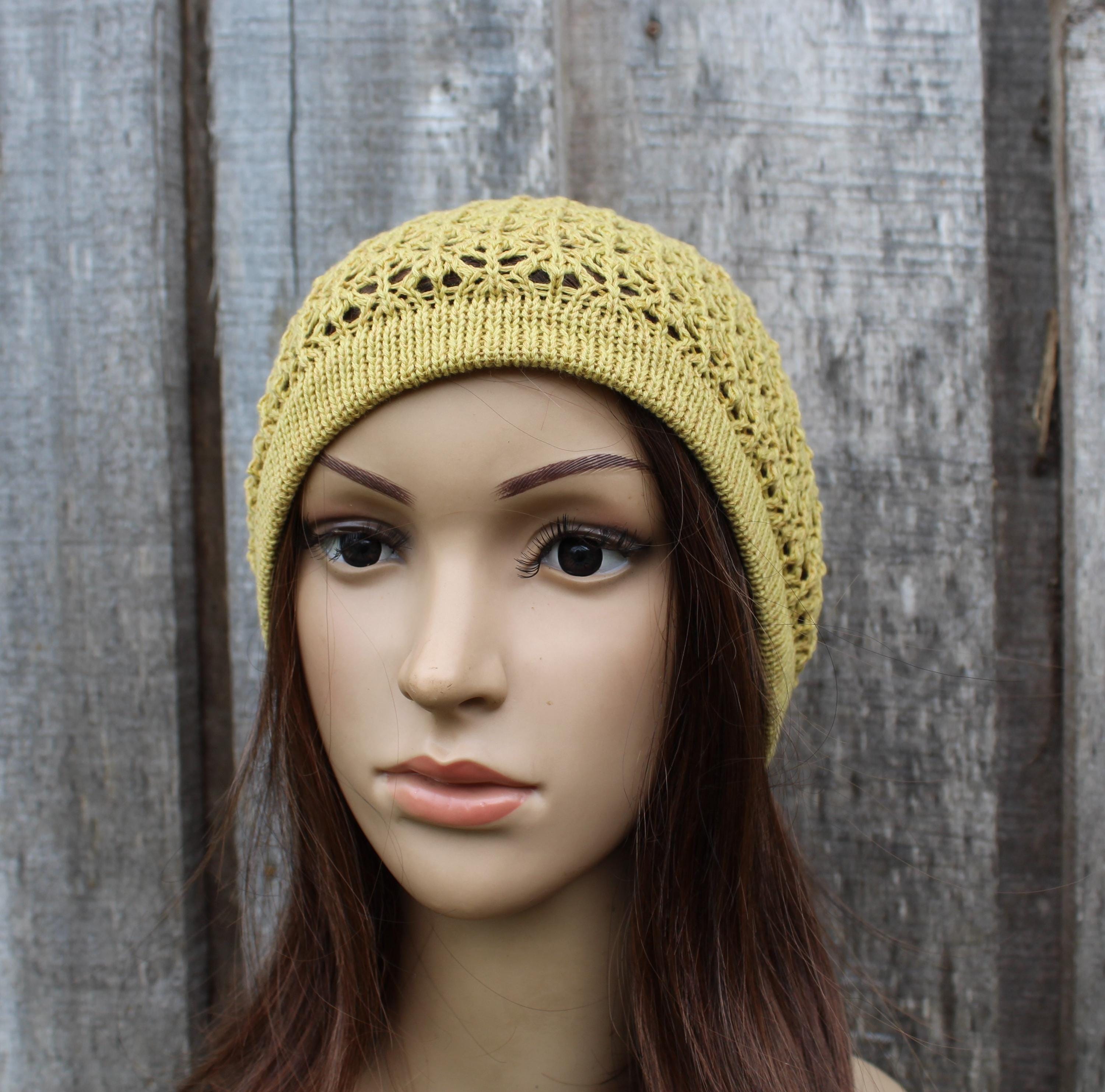 Mannequin head wearing a yellow knitted beanie against a wooden background