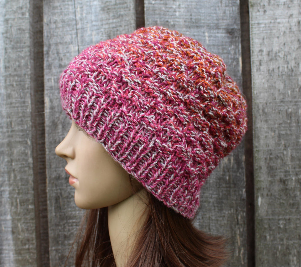 Knitted pink beanie on a mannequin head against a wooden background